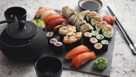 assortment of different kinds of sushi rolls placed on black stone board