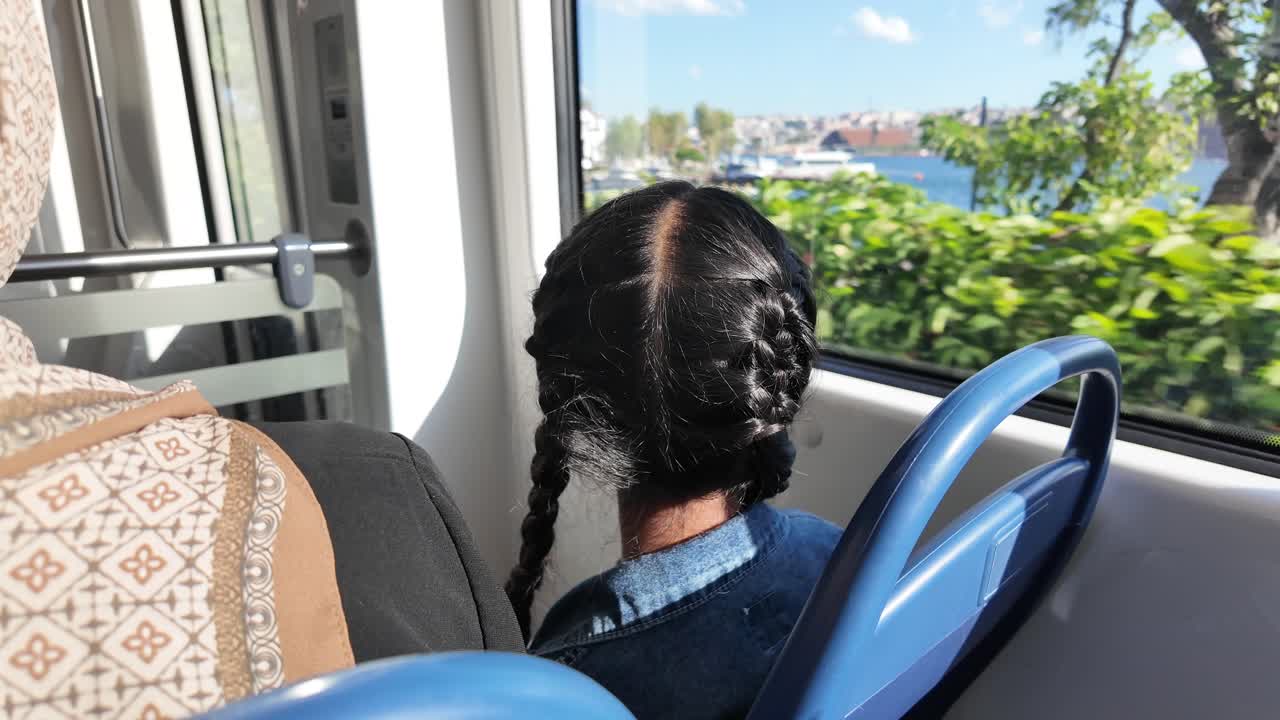 Ragazza con le trecce che guarda fuori dal finestrino di un treno