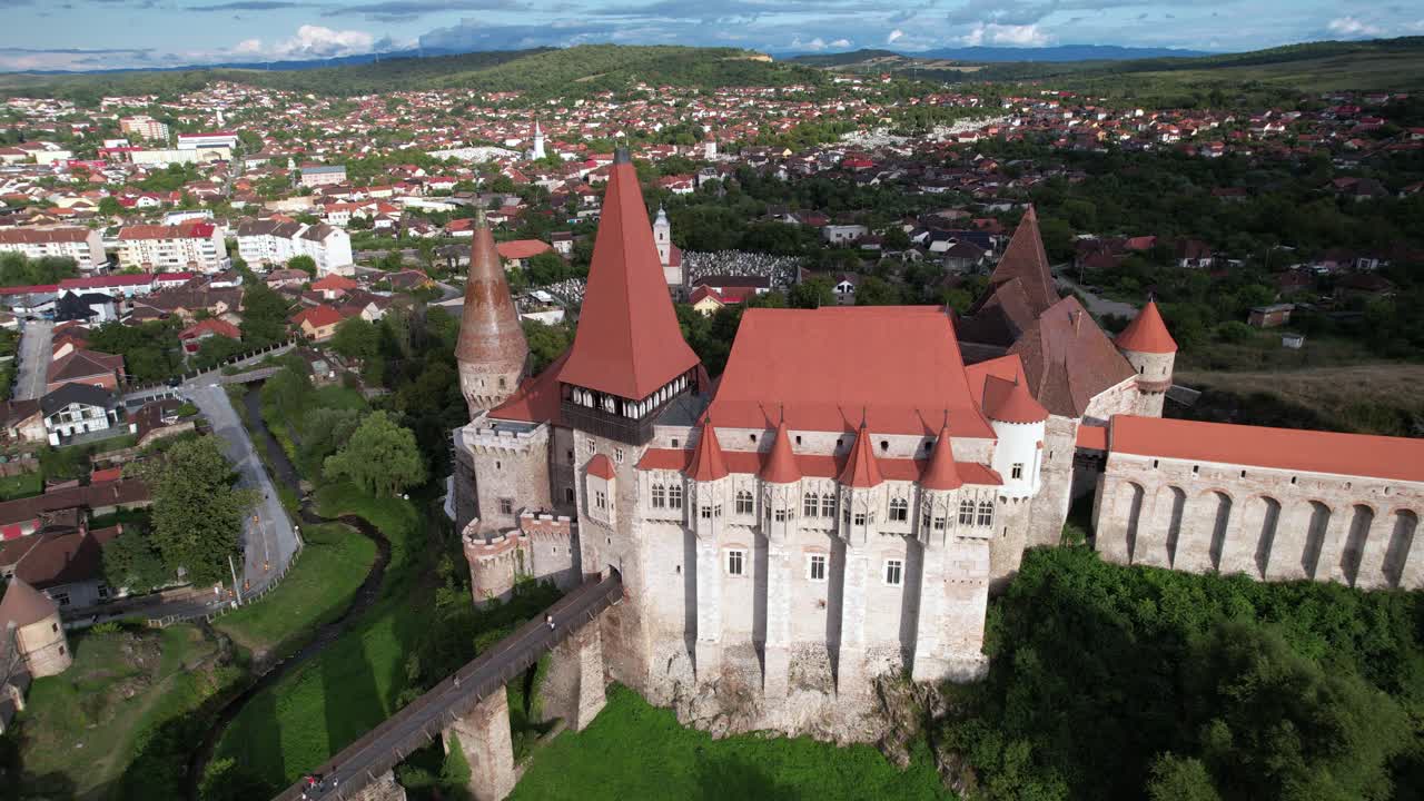 Majestic Corvin Castle in Romania. Panoramic orbiting aerial view over the Gothic Castle, green landscape and Transylvania.