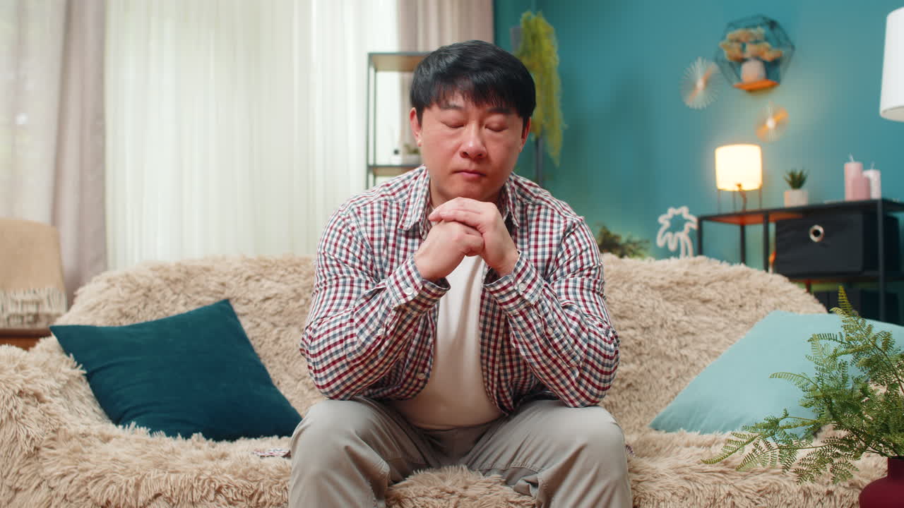 Asian man holding head leaning forward showing deep emotional fatigue heavy stress long work day