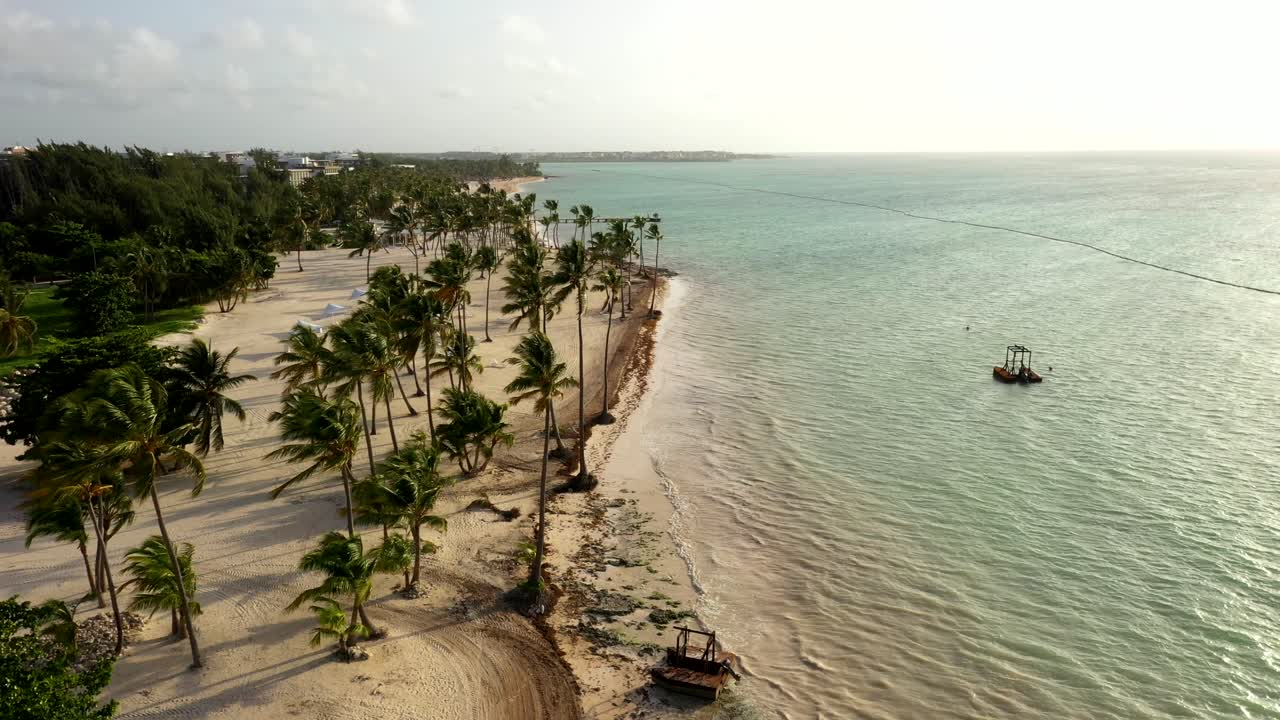 Aerial of beach shoreline and resort surrounded by palm trees, Cap Cana Juanillo Beach Dominican Republic at golden hour