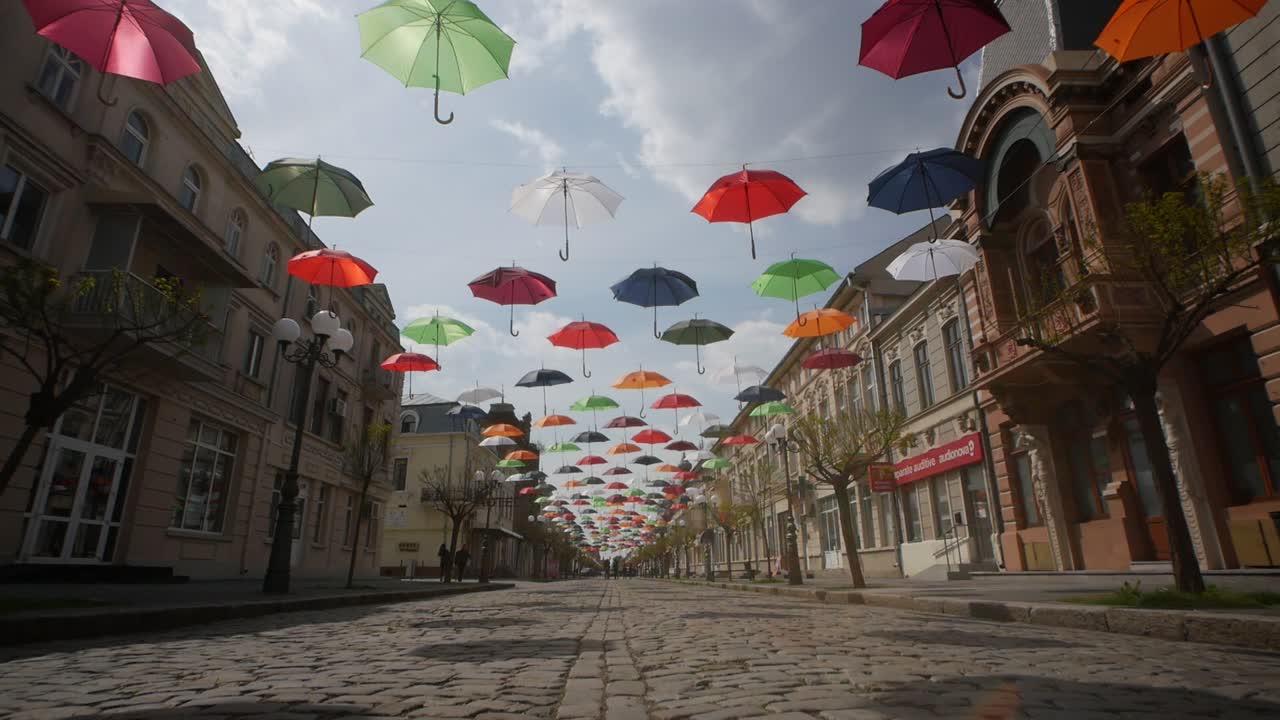 Braila, Romania. April 24 2019 The old central part. Cobbled street. Ancient architecture and multicolored umbrellas hanging in the air. Artistic atmosphere.
