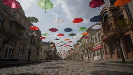 braila, romania. april 24 2019 the old central part. cobbled street. ancient architecture and multicolored umbrellas hanging in the air. artistic atmosphere.