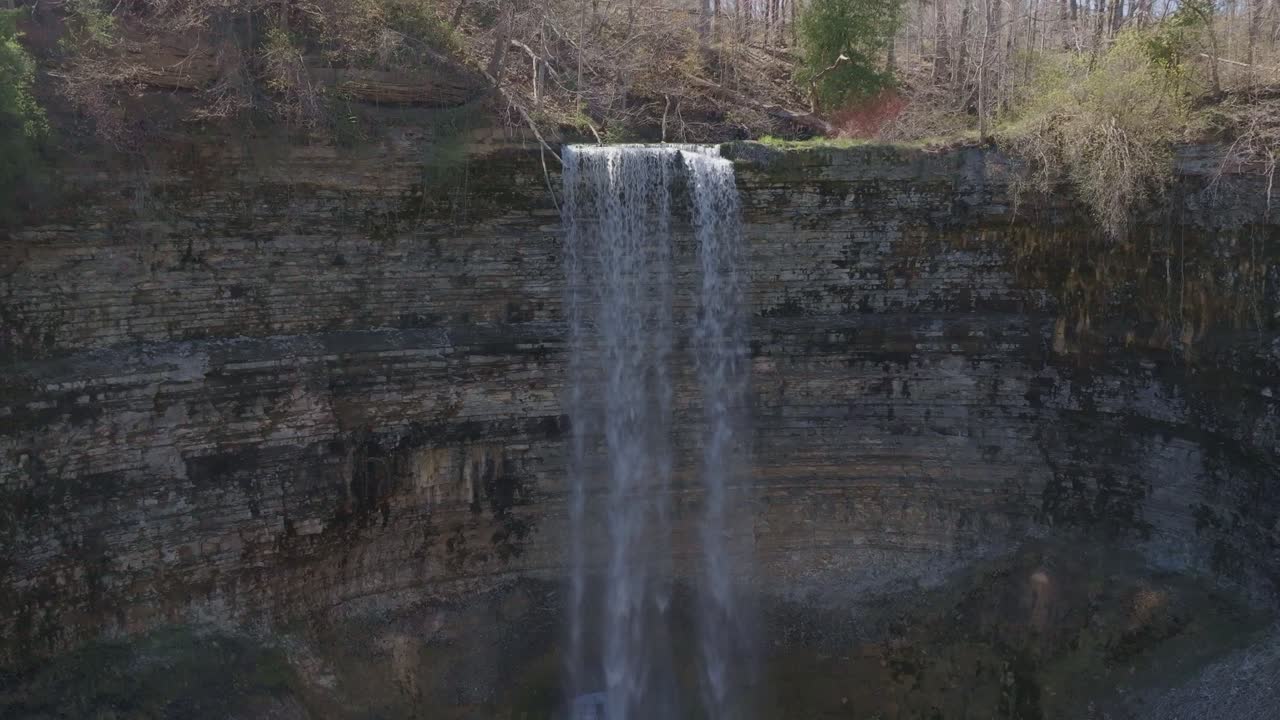 majestuosa cascada que cae por un acantilado rocoso en una cuenca profunda rodeada de bosque
