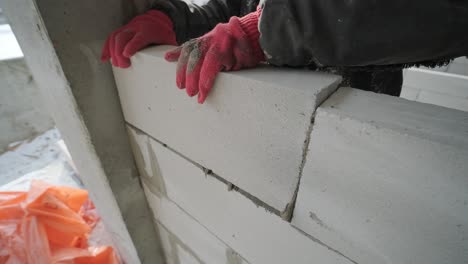 el maestro realiza la colocación de una pared de bloques de gas con herramientas y mortero adhesivo