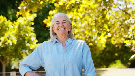 portrait of smiling senior woman standing outdoors in garden park or countryside