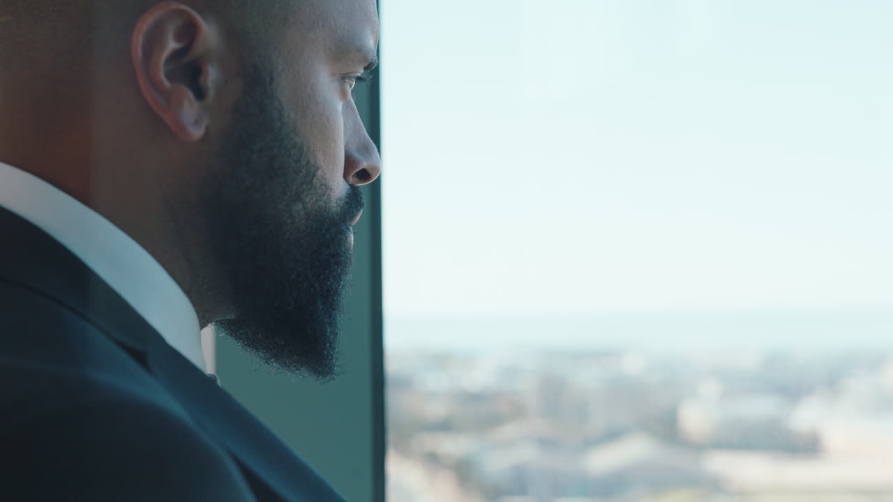 hombre de negocios serio mirando por la ventana planeando hacia adelante pensando en ideas para el futuro desarrollo empresarial con vistas a la ciudad