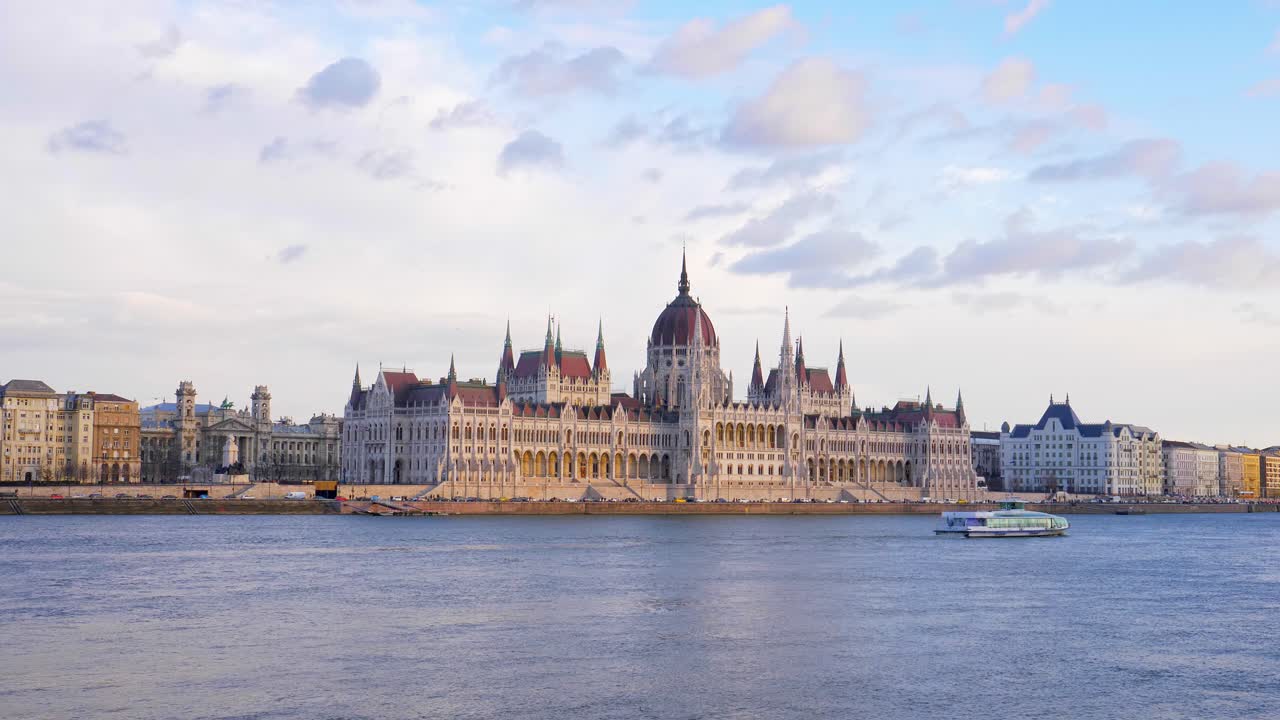 Yacht sailing along the Danube river in front of the Hungarian Parliament building. Golden hour. Budapest, Hungary