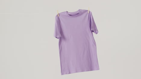 video de un primer plano de una camiseta púrpura colgada sobre un fondo blanco