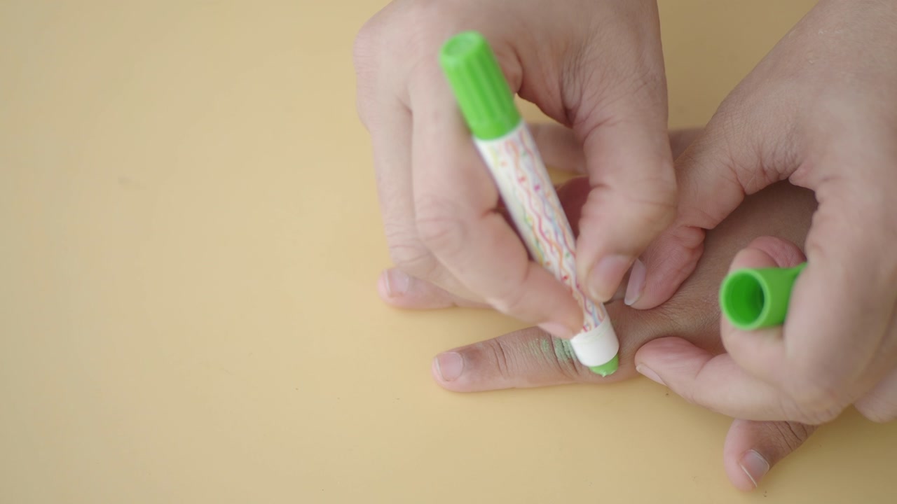 Adult Hand Coloring Child's Fingers with Green Crayon