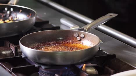 chef pours sherry wine in the pan in order to flame the sauce for the foie gras before browning it