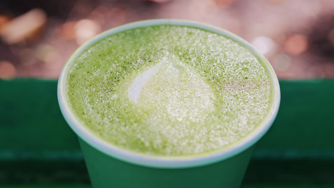 Close up of a frothy matcha latte with heart-shaped latte art