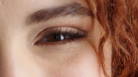 close-up of a woman's eyes and face with red curly hair