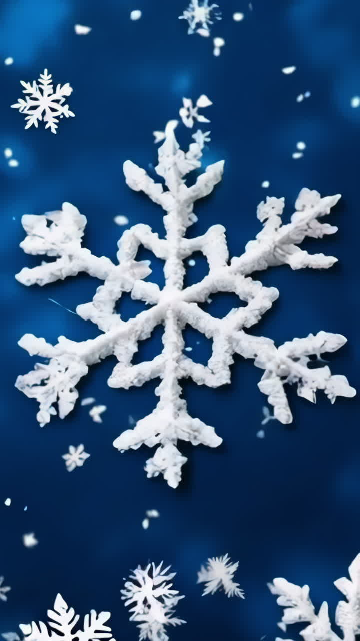 A blue background with snowflakes and a snowflake in the center. The snowflakes are all different sizes and shapes Vertical video