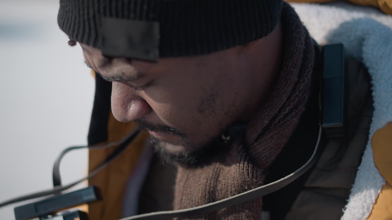 close up aerial view of cameraman sipping juice through straw holding digital camera while looking around urban street with blur of cars and buildings in sunlit soft winter daylight