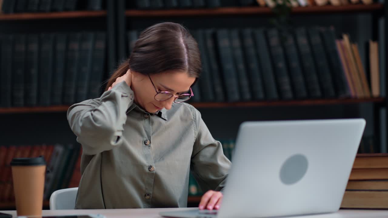 Tired business teacher science woman working at library desk laptop feeling neck pain workaholism