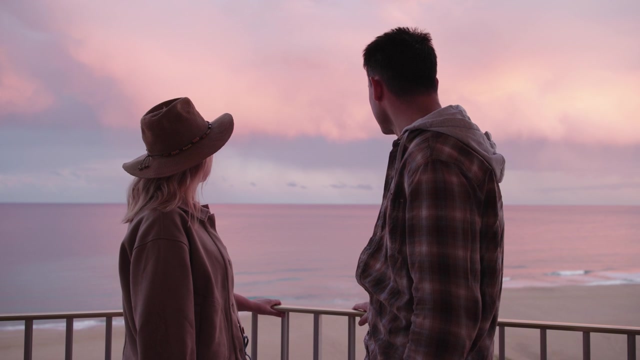 Romantic Couple on Balcony Overlooking Ocean at Sunset