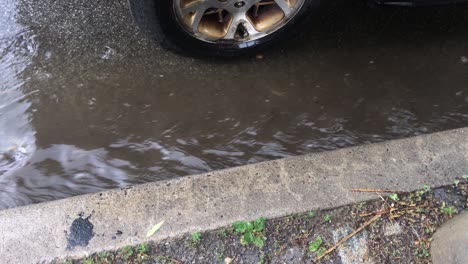 a stream running past a car tire, in a wet urban area