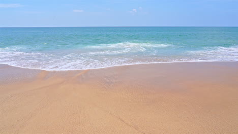 slow-motion of waves washing up on a golden sandy beach