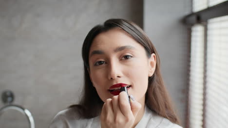 mujer aplicando lápiz labial rojo