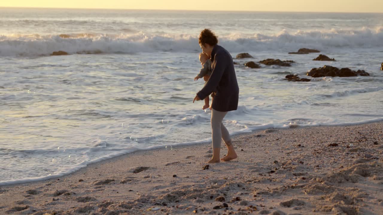 엄마와 아기 소년이 해변에서 놀고 있습니다.