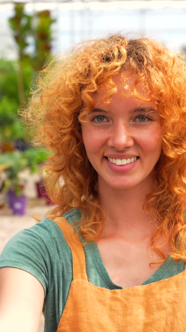 Woman with red curly hair in greenhouse