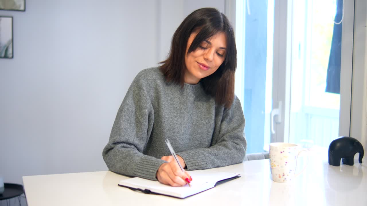 mujer escribiendo en un cuaderno en su escritorio