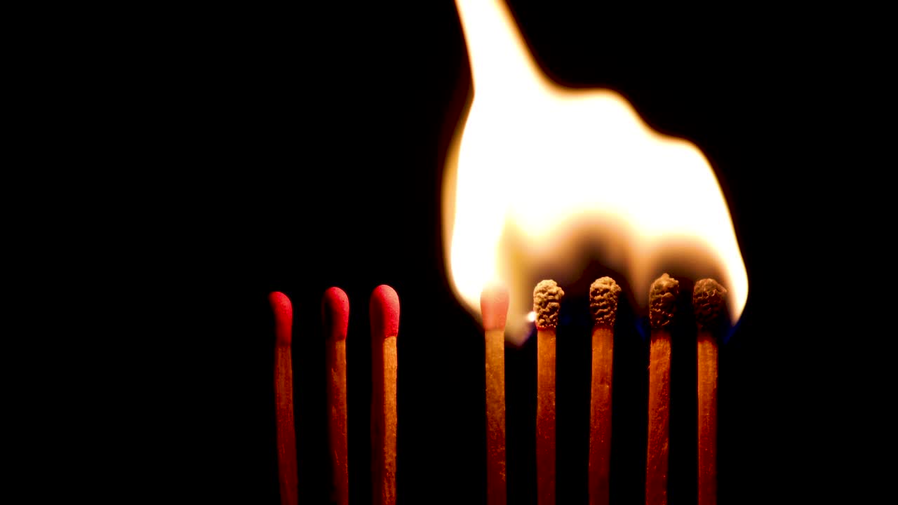 검은색 배경에서 일련의 점화 매치 스틱. 매치 스을 태우는 비디오. 사회적 거리 두기 개념 영상. 도미노 효과. 전염병의 확산을 멈추기.