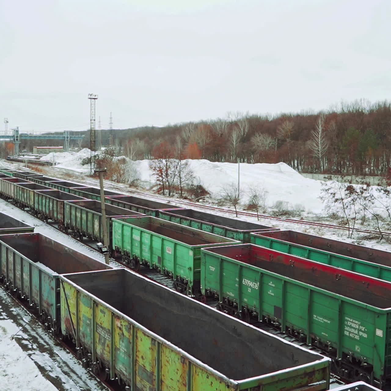 Long rows with old cargo containers for the transport of imports and exports stand on the edge of the forest in the winter on the border zone. Aerial view.