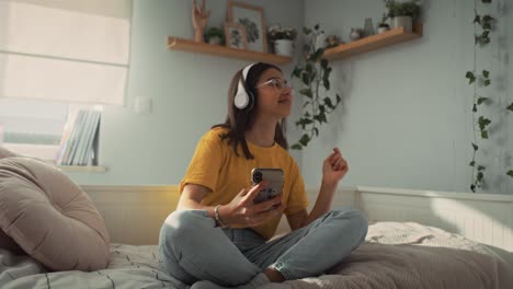 zoom fuera de caucásica adolescente usando auriculares y escuchando música de su teléfono