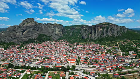 Luftdrohnenflug-über-Einer-Stadt-Mit-Bergen-Im-Hintergrund-An-Einem-Sonnigen-Tag-Mit-Bewölktem-Himmel,-Zeitlupe-Und-Kopierraum,-Sehr-Farbenfroh