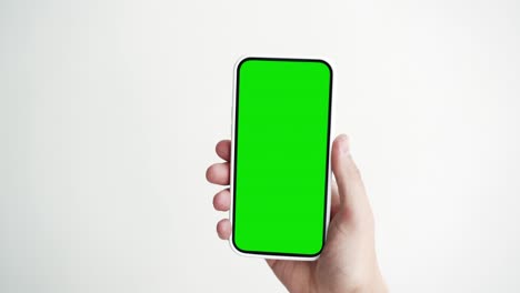 joven utiliza un teléfono inteligente con pantalla verde chroma clave de primer plano. chico sostiene en la mano un teléfono celular mock-up pov. concepto ver y mostrar internet redes sociales, llamadas de video, leer noticias, aplicación, iot, compras electrónicas