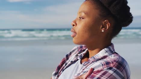 african american woman looking away at the beach on sunny day