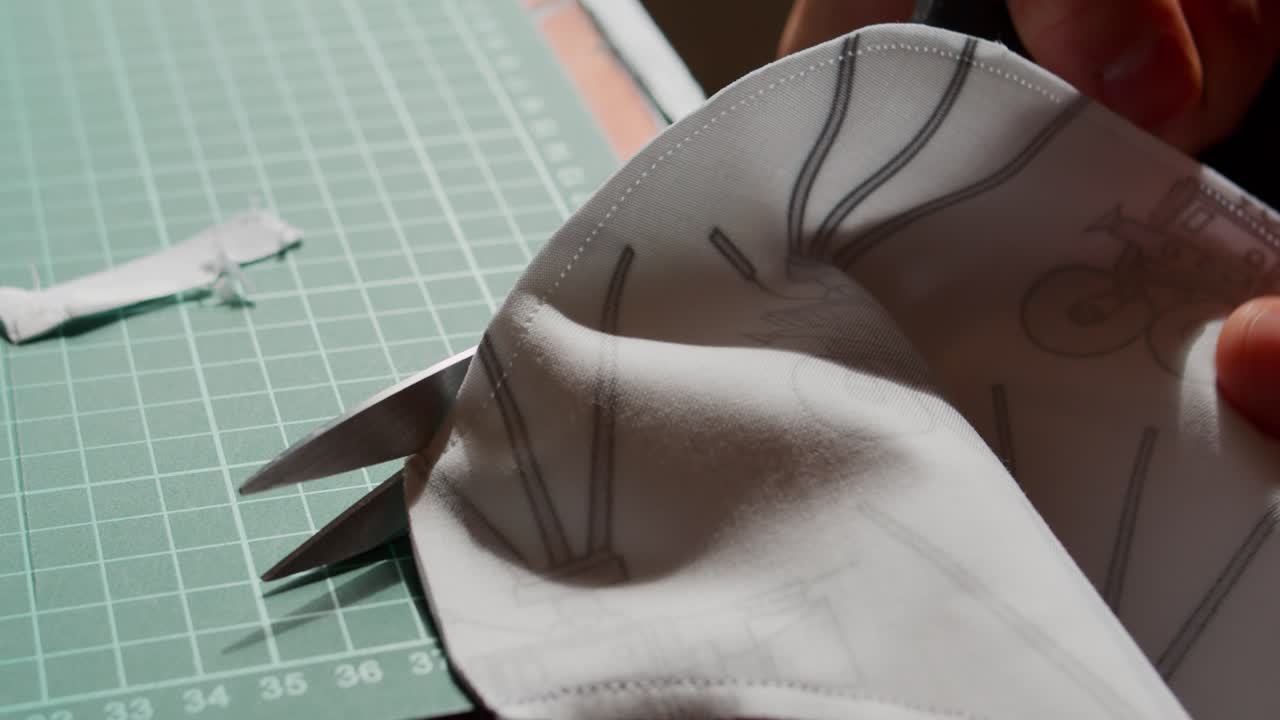 Cutting around a sewn edge of fabric on a table with backlighting