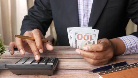 un hombre de negocios contando dinero con una calculadora.