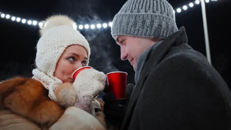 couple enjoying hot drinks outdoors in the winter