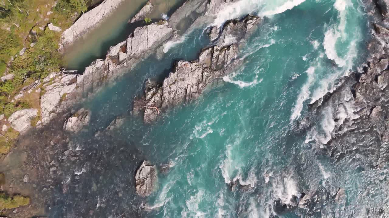 Veduta aerea a volo d'uccello di un fiume che scorre tra le rocce, mostrando la bellezza naturale del paesaggio e il movimento dinamico dell'acqua.