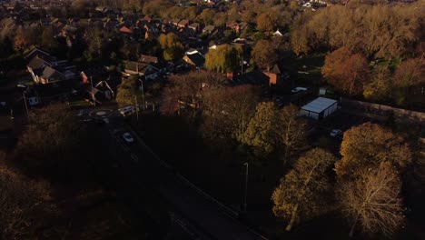 english countryside village road surrounded by autumn trees during golden hour aerial view