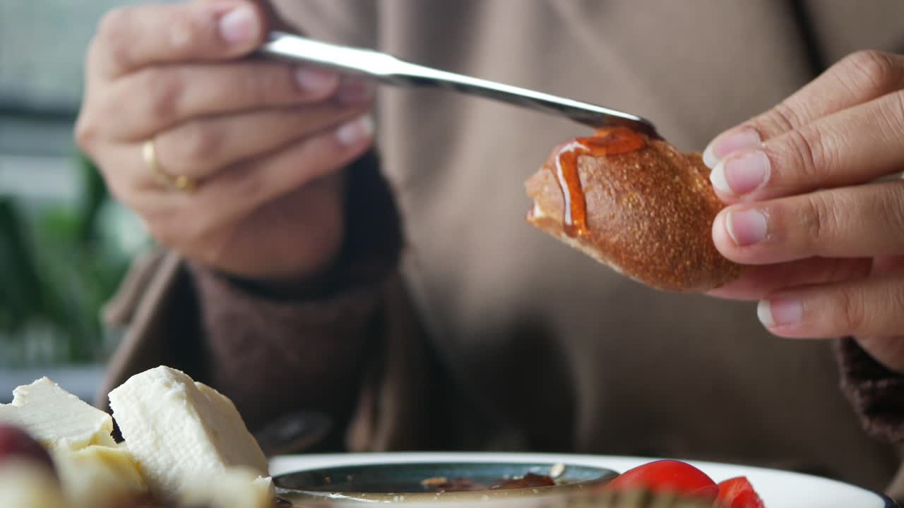 Close-Up of Hands Spreading Jam on Bread During Breakfast