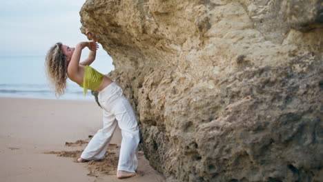 talented woman dancing improvisation near beach rock. girl dancer bending body