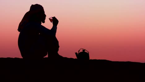 Ein-Beduinenmann-Gießt-Tee-In-Silhouette-Gegen-Den-Sonnenuntergang-Ein