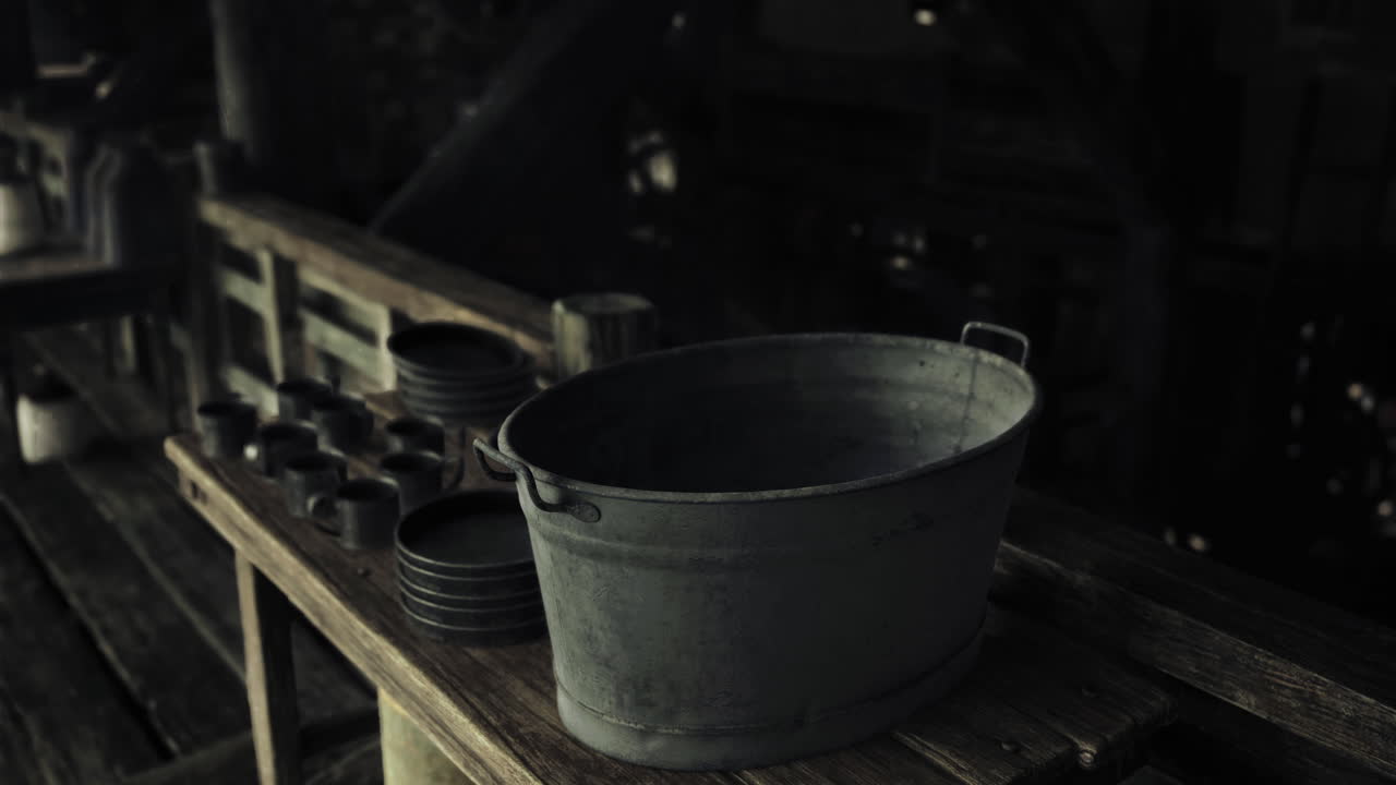 Rustic wooden table with metal bucket and ceramic dishes in dim light