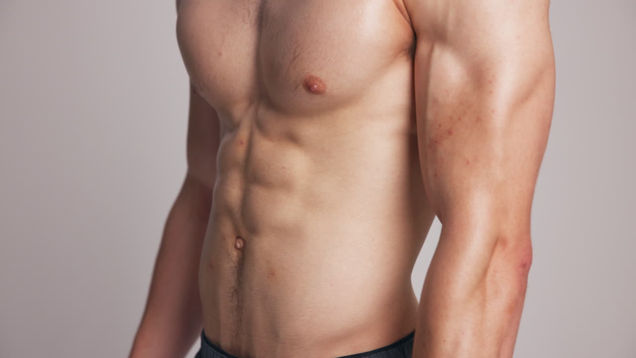 Homem musculoso exibindo os músculos abdominais em estúdio