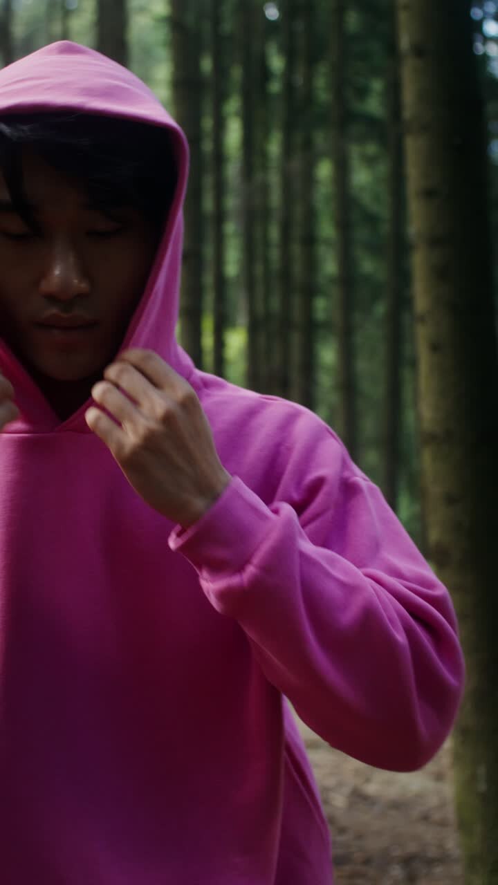 Uomo con felpa rosa nel bosco
