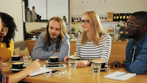 grupo grupo multiétnico de amigos hablando sentados en una mesa en un café