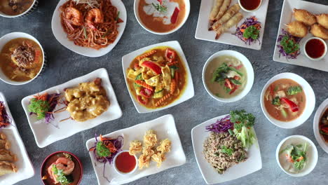 male hand placing down bowl of thai red curry onto flat lay arrangement