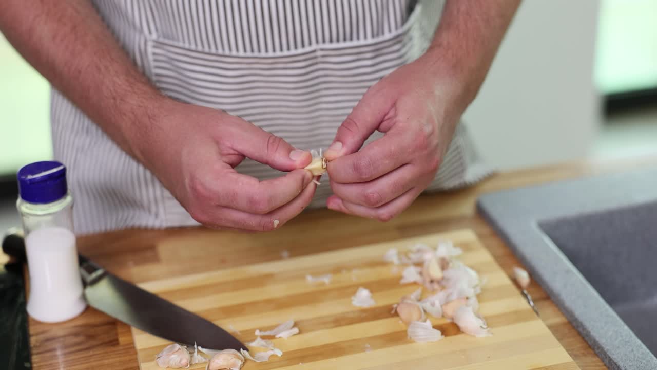 Close-up of hands peeling garlic cloves on a wooden cutting board