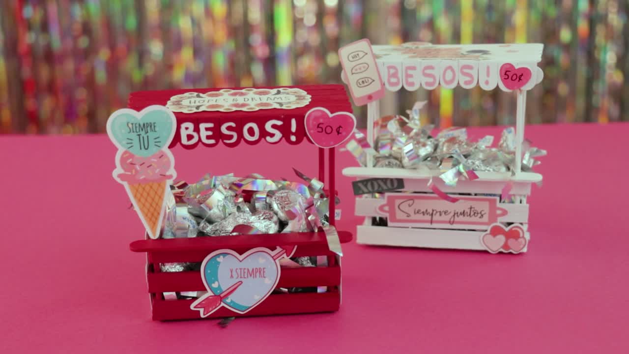 el mini beso de san valentín está lleno de dulces envueltos, colocado en una mesa rosada vibrante con decoración
