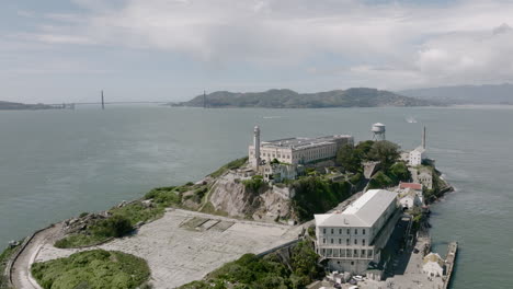 Aerial-rotating-shot-of-Alcatraz-Prison-Island-with-Golden-Gate-Bridge-in-background-in-San-Francisco,-CA