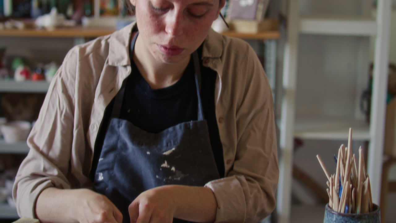 Ceramista donna che modella un piatto di argilla con bordo ondulato in uno studio di ceramica
